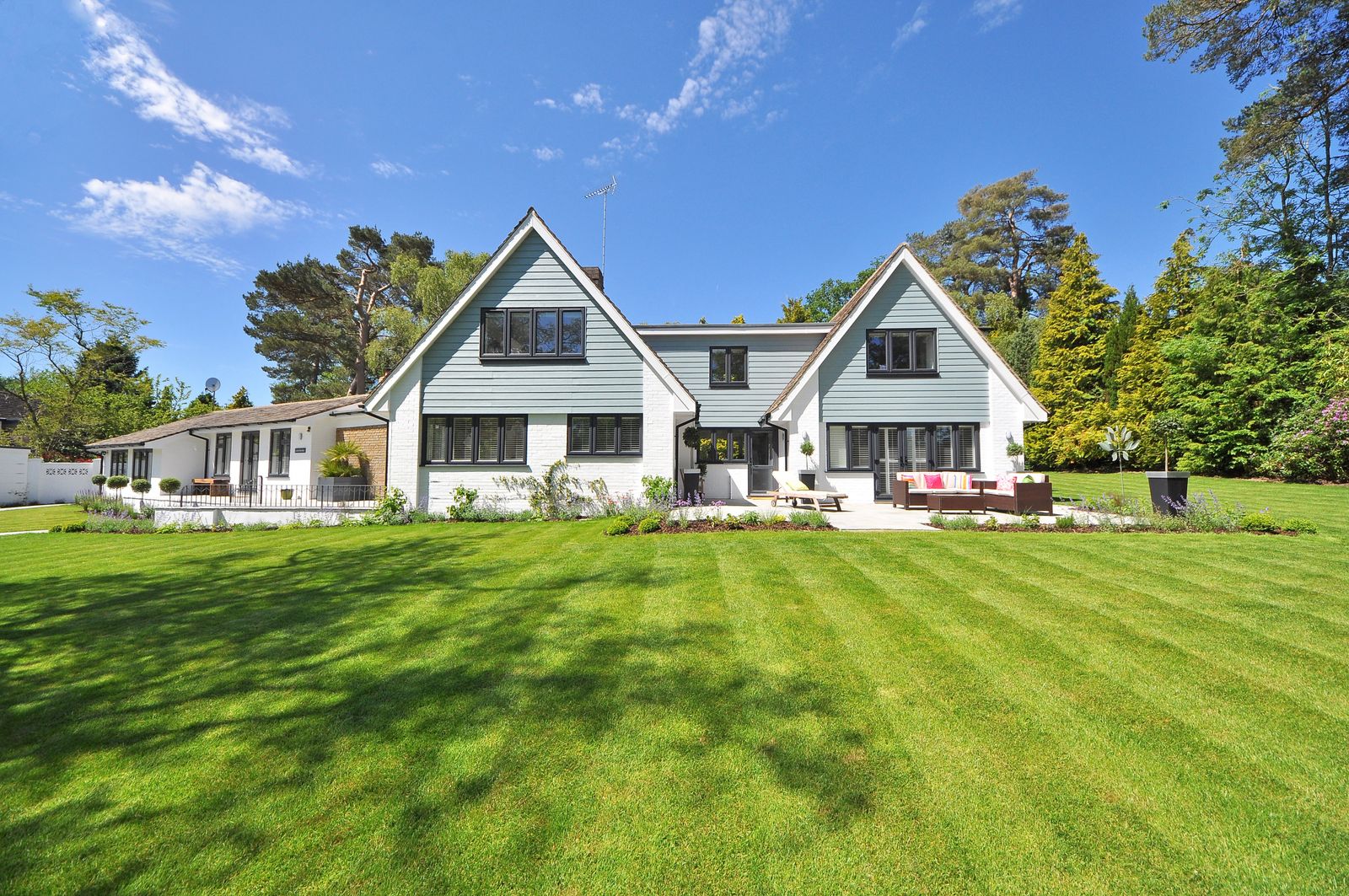 A striped lawn and planted borders in front of a well-kept house