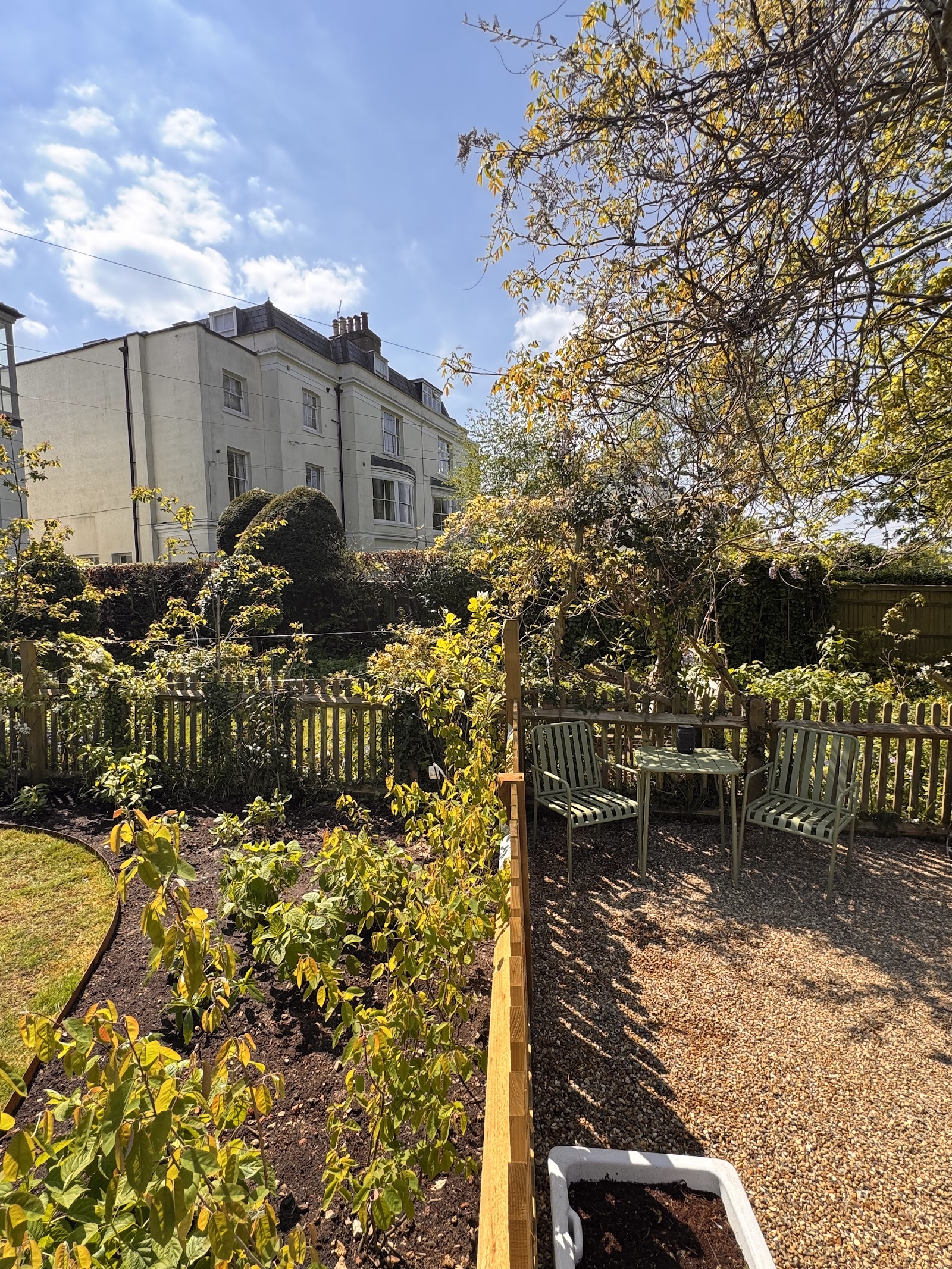 A kitchen garden zoned off with timber fencing and a gravel seating corner.